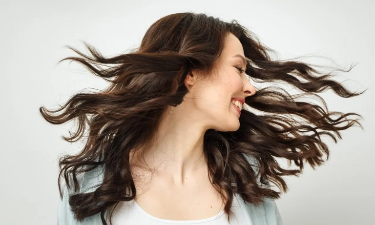 Photo of a woman with long dark hair turning her head and her hair is twirling in the air for the O-Shot at The Hughes Center in Cherry Hill