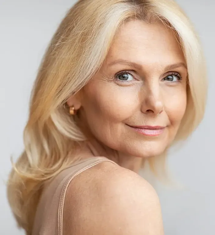Photo of a happy senior woman looking over her shoulder at the camera cropped