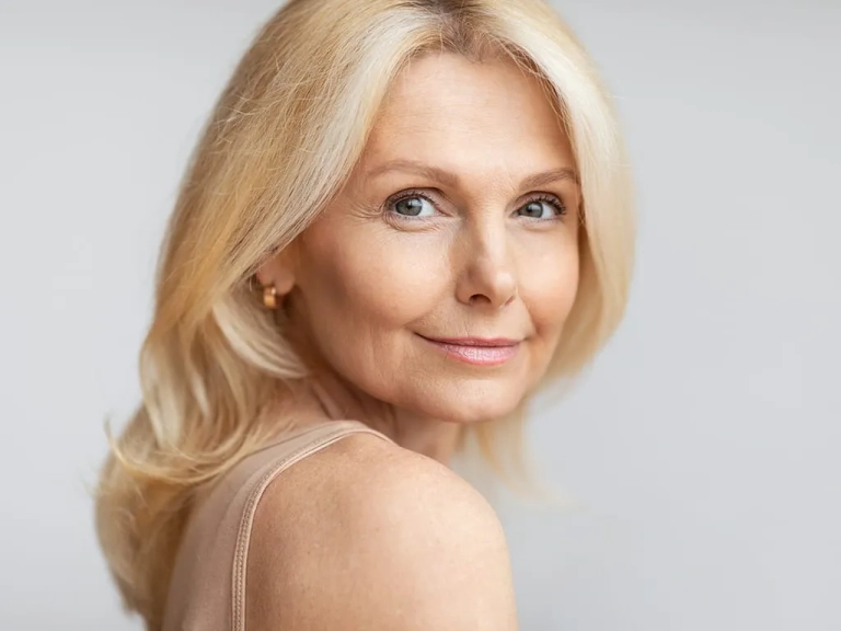 Photo of a happy senior woman looking over her shoulder at the camera for Genius RF Microneedling at The Hughes Center in Cherry Hill NJ