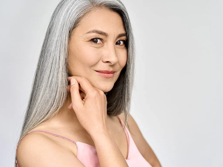 Photo of a woman with long black and gray hair touching her face for Emface Submentum at The Hughes Center in Cherry Hill NJ